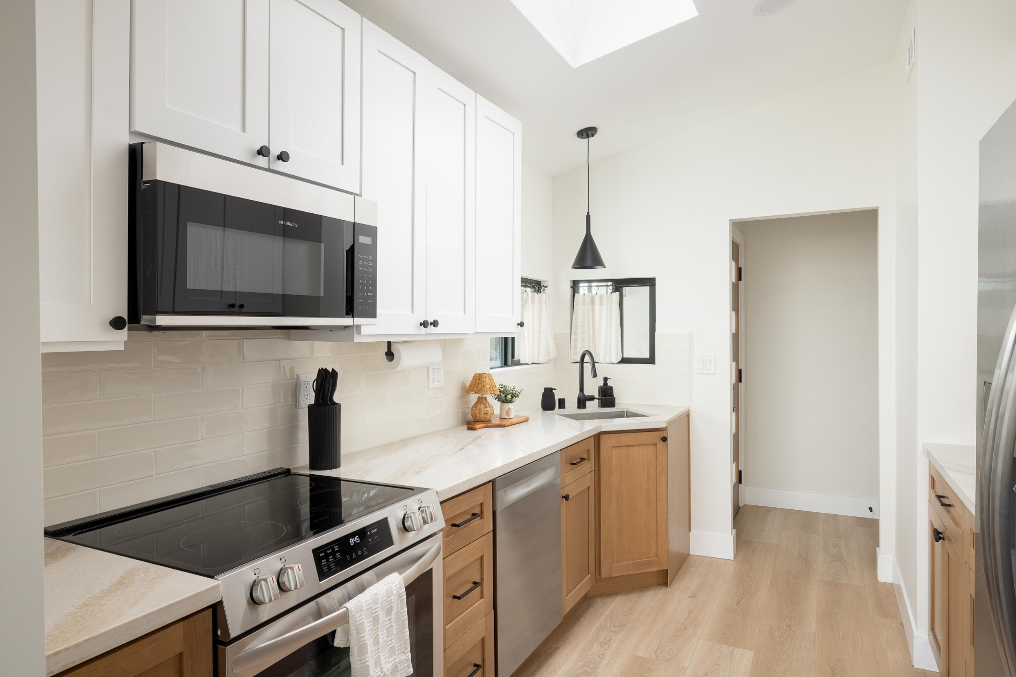 Completed kitchen with white upper cabinetry and warm wood lower cabinets
